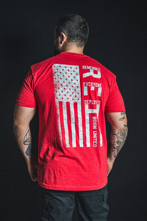 A man is facing away, wearing the Born United Private Label RFV2 red t-shirt featuring an American flag and the words “Remember Everyone Deployed V2” and “Born United” printed on the back.