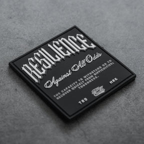 The Resilience - Patch by Tango Charlie Apparel features a black 3D PVC design with “RESILIENCE” in bold white on grey, “Against All Odds” below, plus text defining resilience. Credits note TTD, MRK, and Savage Supply Co. It’s a 3-inch Velcro patch.