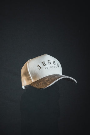 An Ivory and Deadwood Camo Jesus is King snapback by Born United Private Label, featuring “JESUS IS KING” embroidered on the front and displayed against a dark background.