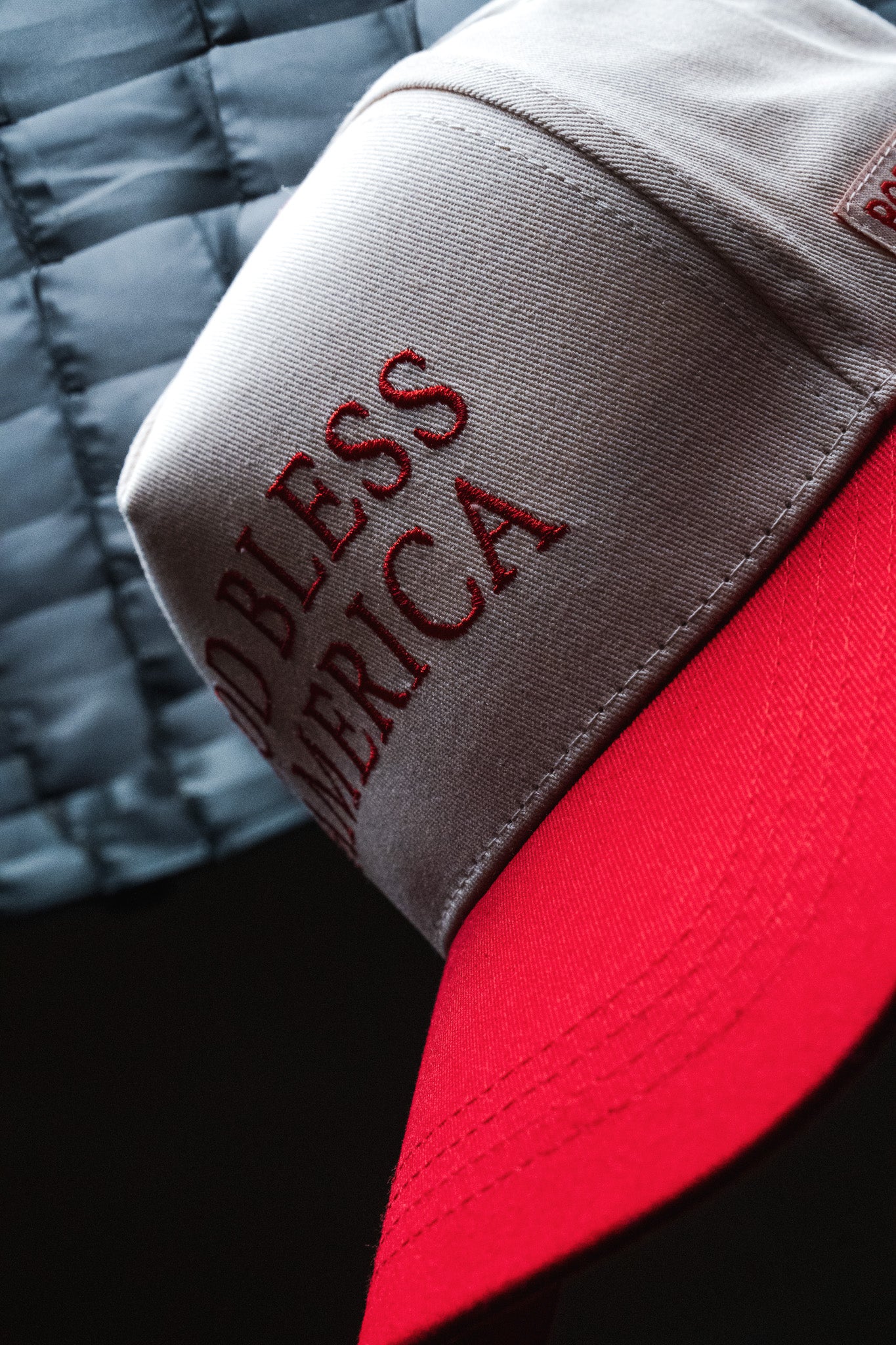 A close-up of the Born United Private Label God Bless America Snapback, showcasing its red and white embroidery with “GOD BLESS AMERICA” boldly stitched on the front, perfectly capturing the patriotic spirit of this classic cap.