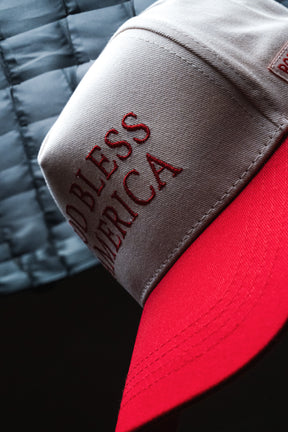 A close-up of the Born United Private Label God Bless America Snapback, showcasing its red and white embroidery with “GOD BLESS AMERICA” boldly stitched on the front, perfectly capturing the patriotic spirit of this classic cap.