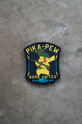 The Pika Pew PVC Patch by Born United Private Label features Pikachu in a helmet with a rifle, "PIKA-PEW" at the top, "LIVE FREE BORN UNITED" at the bottom, and a blue-striped flag—a must-have for Pokemon fans!.