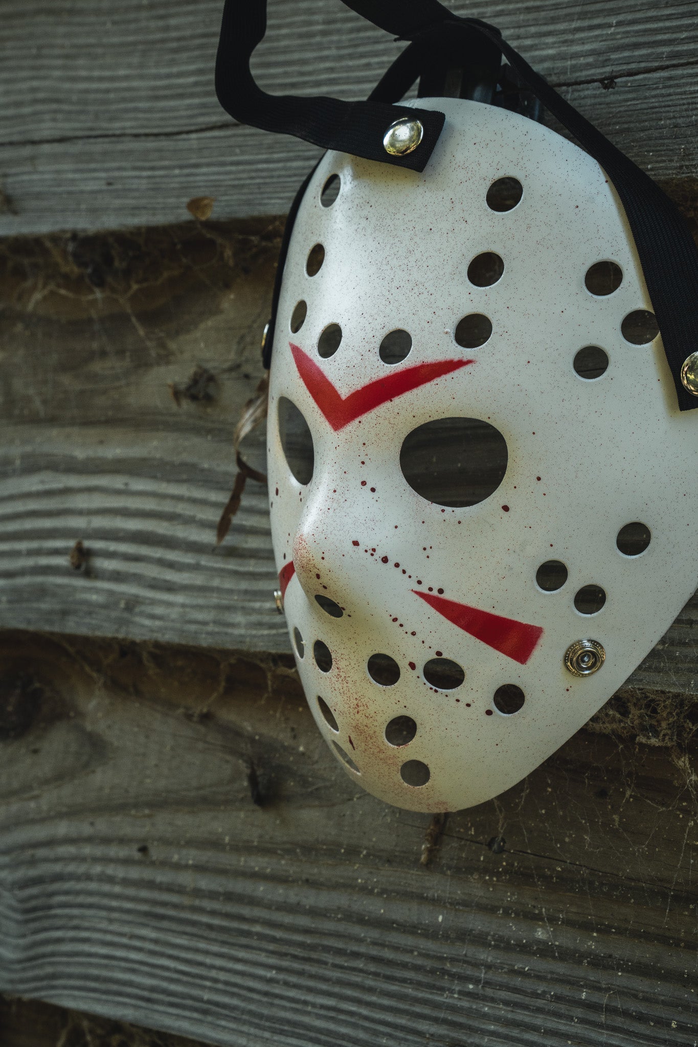 Operation Nightmare Tee - Glow in the Dark white hockey mask with glow-in-the-dark red accents hanging against a weathered wooden surface.