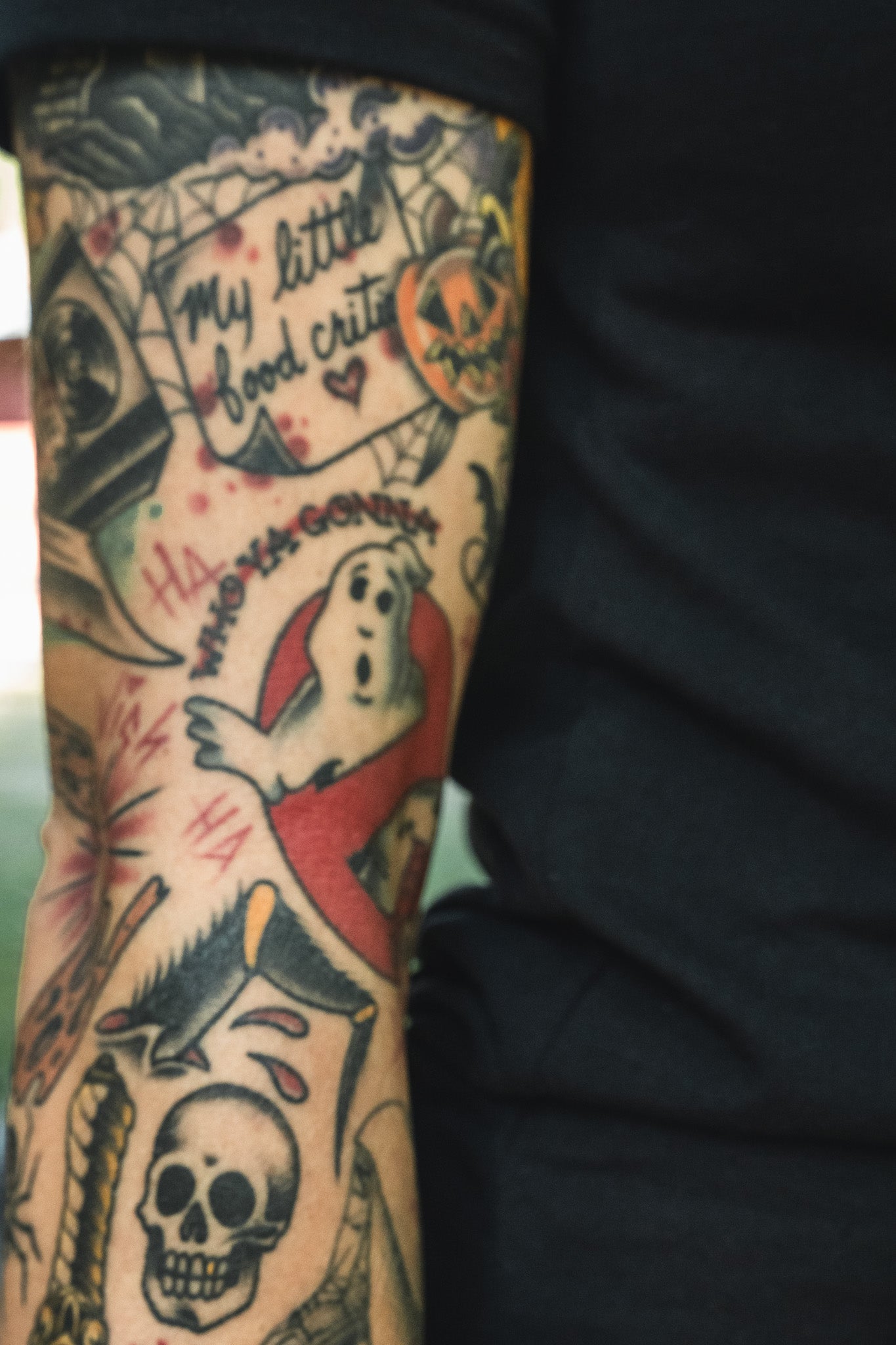 Arm covered in Operation Nightmare Tee - Glow in the Dark horror-themed tattoos, including a ghost, a skull, and the text My little food critter.
