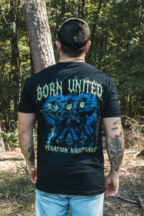 Back view of a man wearing a black Operation Nightmare Tee - Glow in the Dark featuring three masked tactical figures with BORN UNITED and OPERATION NIGHTMARE text.