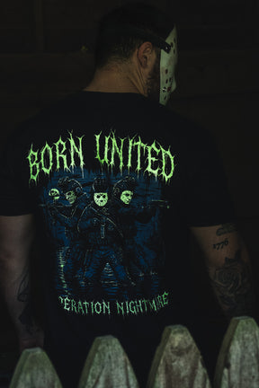 A person wears a black Operation Nightmare Tee - Glow in the Dark, featuring a glow-in-the-dark graphic of three armed figures in hockey masks with drippy green lettering.
