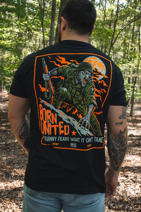 Back view of a person wearing a black Full Moon Tee, featuring a graphic of an armed werewolf in military gear, an orange full moon, and the text: Born United: Tyranny fears what it cant tame.