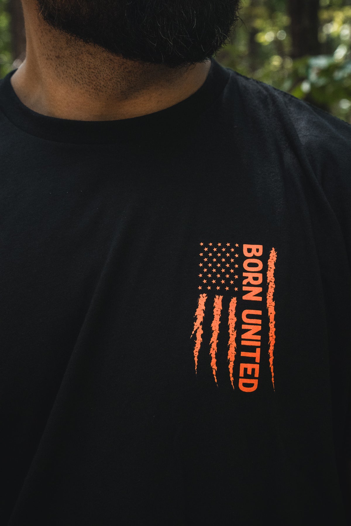 Full Moon Tee: a black t-shirt featuring a distressed orange American flag graphic and vertically oriented text reading BORN UNITED.