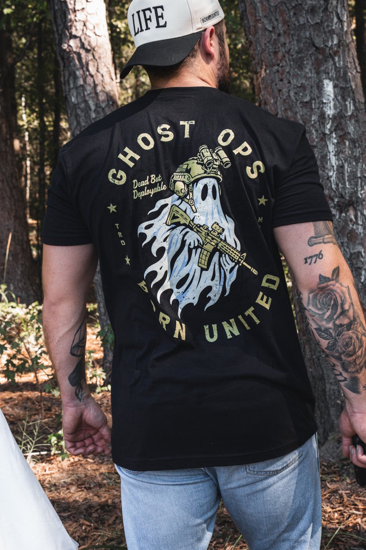 Back view of a person wearing a black Ghost Ops Tee, featuring a graphic of a ghost in tactical gear holding a rifle with the text Dead But Deployable.