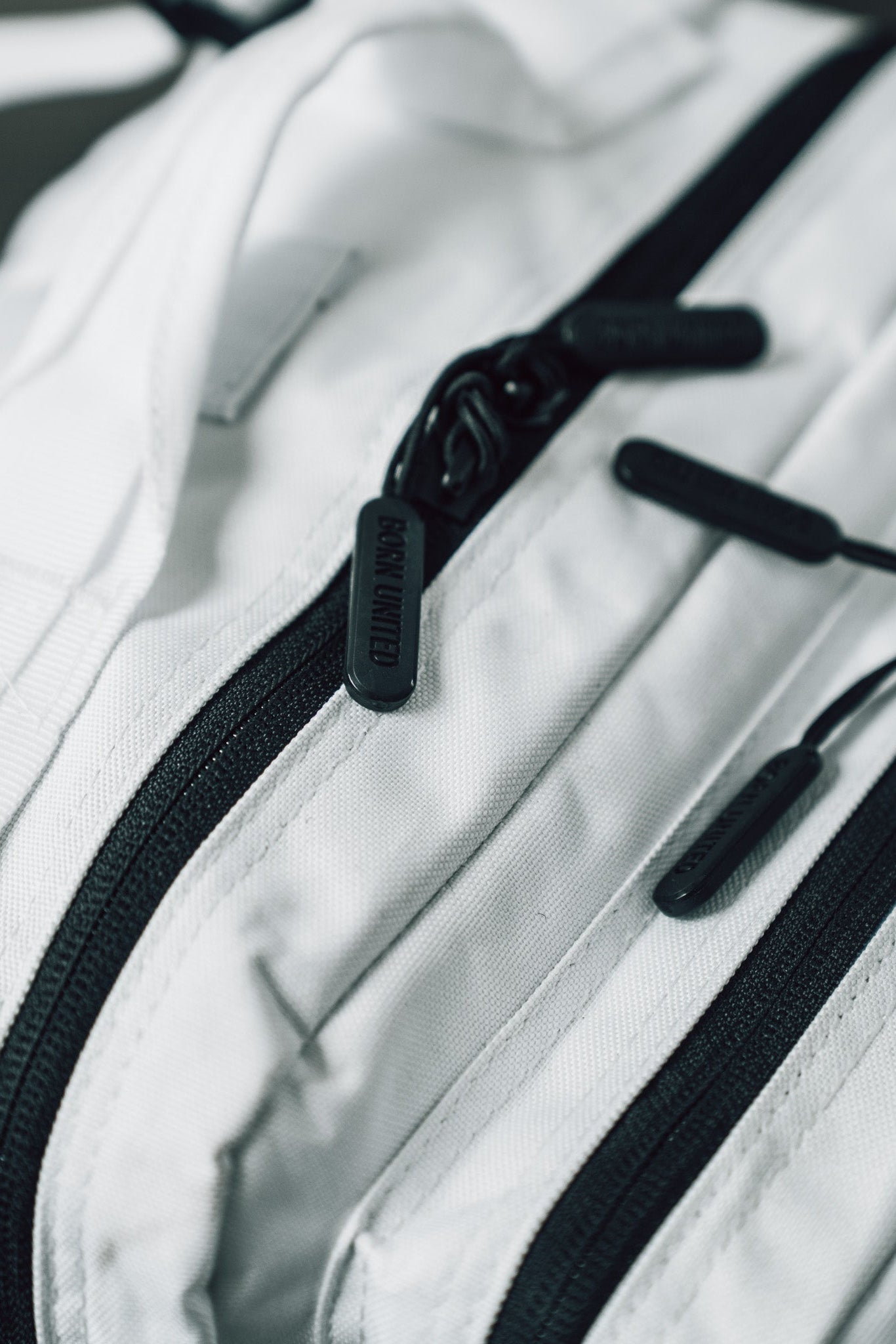 Close-up of the Born United Private Label Storm Trooper Tac-Pac - 45L, a white fabric bag with black zippers and pulls inspired by Stormtrooper armor, showcasing the detailed texture and quality hardware.