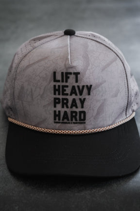 Tango Charlie Apparel’s Lift Heavy. Pray Hard. Deadwood Camo Hydro Snapback Hat features the bold LIFT HEAVY. PRAY HARD. slogan on the front and combines water resistance with durable style, making it ideal for workouts or everyday wear.
