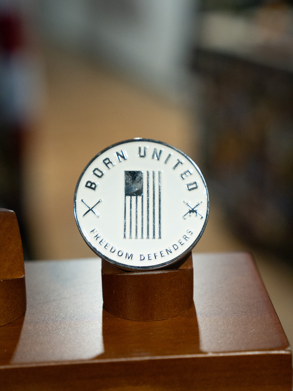 The Outlaw Challenge Coin by Born United Private Label features a round badge with a black and white American flag, “BORN UNITED” above, “FREEDOM DEFENDERS” below, and crossed rifles—perfect for those who protect freedom like outlaws.