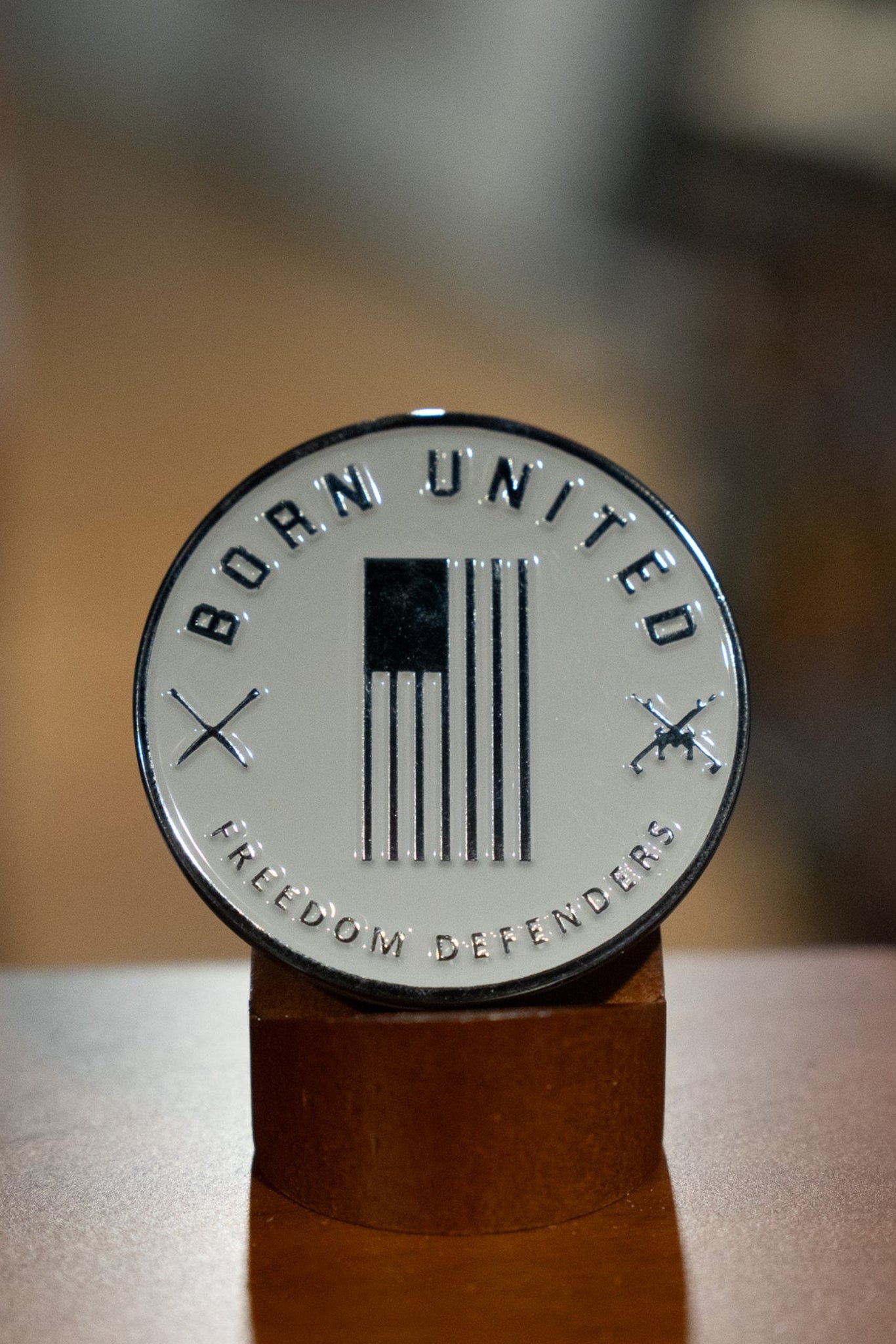 The Brick Operator Challenge Coin by Born United Private Label is a round silver medallion with "BORN UNITED" above, "FREEDOM DEFENDERS" below, a black and white US flag, crossed rifles, and Brick Operator craftsmanship details.
