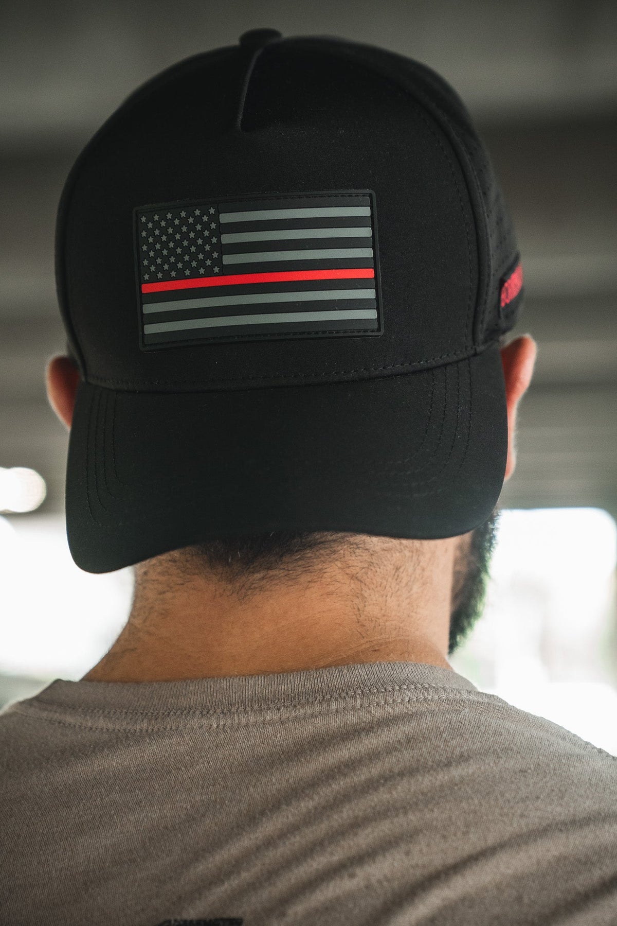 Someone is seen from behind wearing the Born United Premium Flag Snapback - TRL by Born United Private Label, a black cap featuring a monochrome American flag with a single red line on the back.