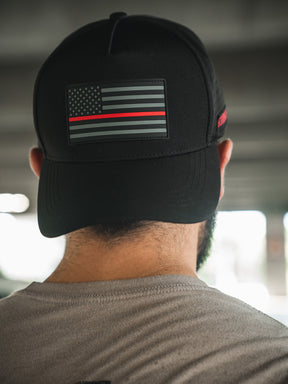 Someone is seen from behind wearing the Born United Premium Flag Snapback - TRL by Born United Private Label, a black cap featuring a monochrome American flag with a single red line on the back.