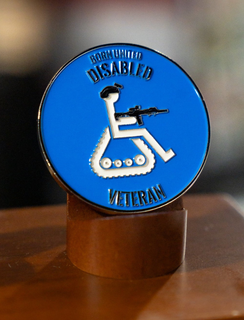 The Born United Private Label Disabled Vet Challenge Coin is a round blue badge featuring "BORN UNITED DISABLED VETERAN" and a stylized wheelchair icon with helmet and rifle, proudly honoring every Disabled Vet.