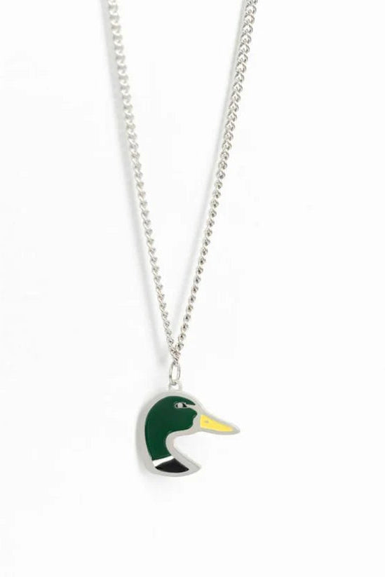 The Mucker Bucket Mallard OG necklace features a ducks head pendant with green and yellow enamel on a silver background, hanging elegantly from a stainless steel chain. Crafted in the USA, it combines quality artistry and craftsmanship.