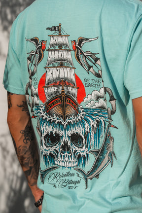 Introducing the To The Ends Of The Earth Premium T-Shirt by Relentless Betrayal—a turquoise unisex shirt featuring a striking graphic of a sailing ship, crashing waves forming a skull, birds, and a shark, along with the text “Relentless as the Ocean, Wild as the Earth.” Crafted from 100% cotton for premium comfort and style.