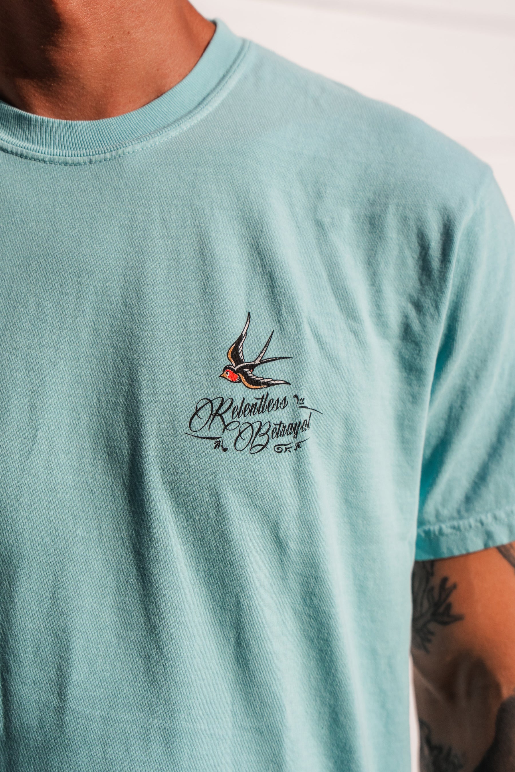 Wearing the To The Ends Of The Earth Premium T-Shirt by Relentless Betrayal—a light blue unisex premium tee featuring a small embroidered swallow and the words Relentless Bazaar on the chest. Made from 100% cotton, this comfortable shirt delivers both style and quality.