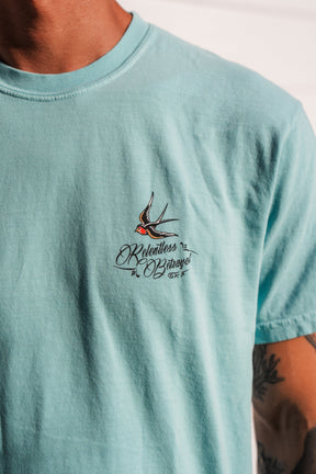 Wearing the To The Ends Of The Earth Premium T-Shirt by Relentless Betrayal—a light blue unisex premium tee featuring a small embroidered swallow and the words Relentless Bazaar on the chest. Made from 100% cotton, this comfortable shirt delivers both style and quality.