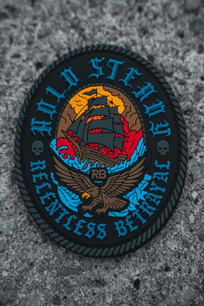 The Hold Steady Patch by Relentless Betrayal is a 3x3" round patch featuring a sailing ship, eagle, skulls, and rope edging in bold blue, red, and yellow with "HOLD STEADY RELENTLESS BETRAYAL" around the border.