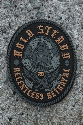 The Hold Steady Ghost Patch by Relentless Betrayal is a 3" 3D PVC patch with a sailing ship and eagle design, “HOLD STEADY” on top and “RELENTLESS BETRAYAL” below. It features Velcro backing and is shown on rough gray concrete.