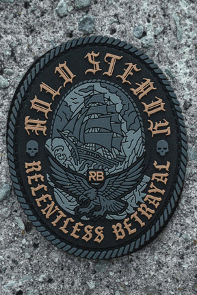 The Hold Steady Ghost Patch by Relentless Betrayal is a 3-inch Velcro patch with an embroidered sailing ship, eagle, RB initials, skull details, and the phrases HOLD STEADY and RELENTLESS BETRAYAL on textured gray.