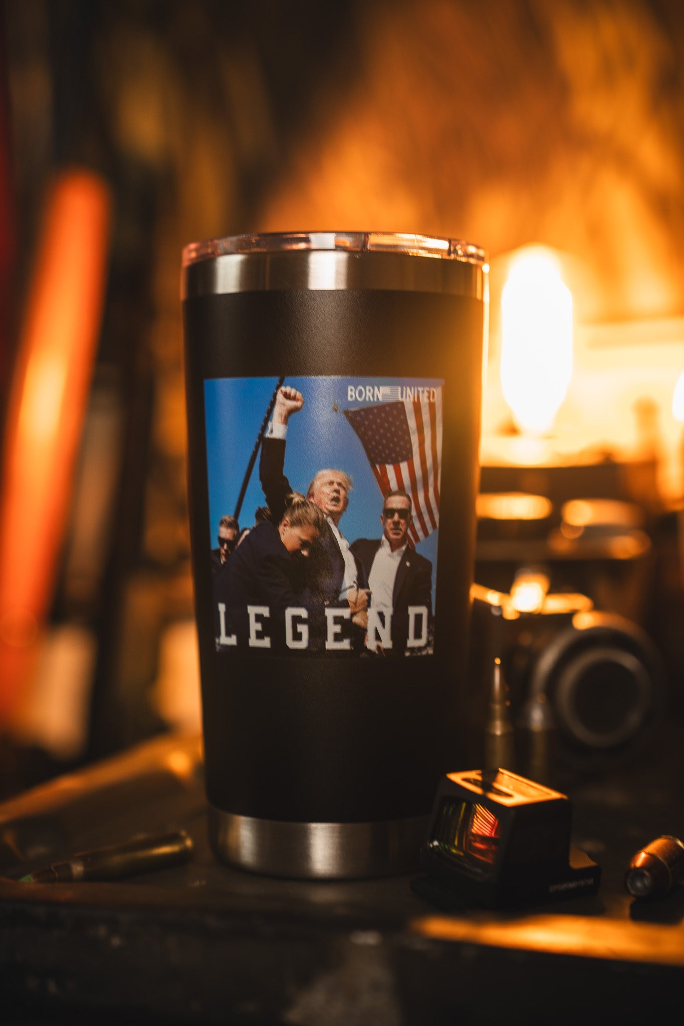 The Born United Private Label Forever Legend Tumbler - 20oz is a stainless steel travel mug featuring an image of a man holding an American flag with "LEGEND" below, photographed in a warmly lit room with blurred background.