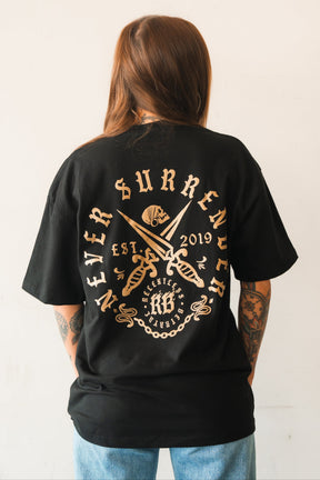 A person with long brown hair and tattoos wears the Relentless Betrayal Never Surrender Premium Oversized Ghost T-Shirt, featuring a bold back graphic of crossed swords, a skull, “Never Surrender,” “Est. 2019,” and decorative text.