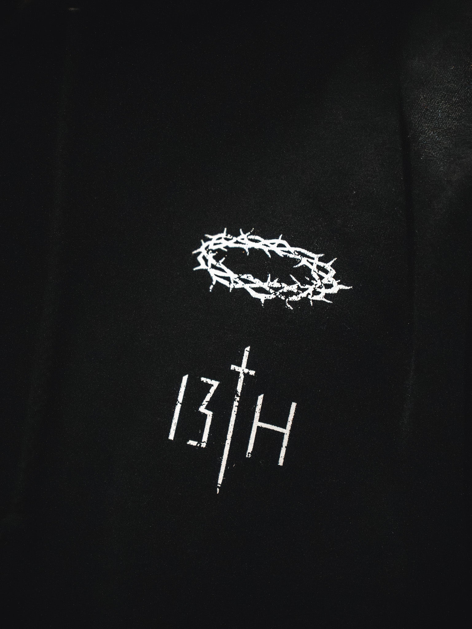 The 13th brand’s Jesus Saves Hoodie is black, with a white thorn crown above “13TH”—the “T” is shaped like a cross.