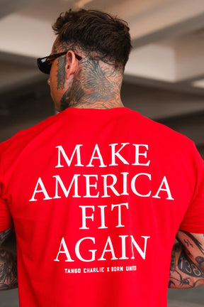A tattooed individual in sunglasses and a bright red Make America Fit Again - Tee by Tango Charlie Apparel stands indoors with their back to the camera, promoting health and wellness.