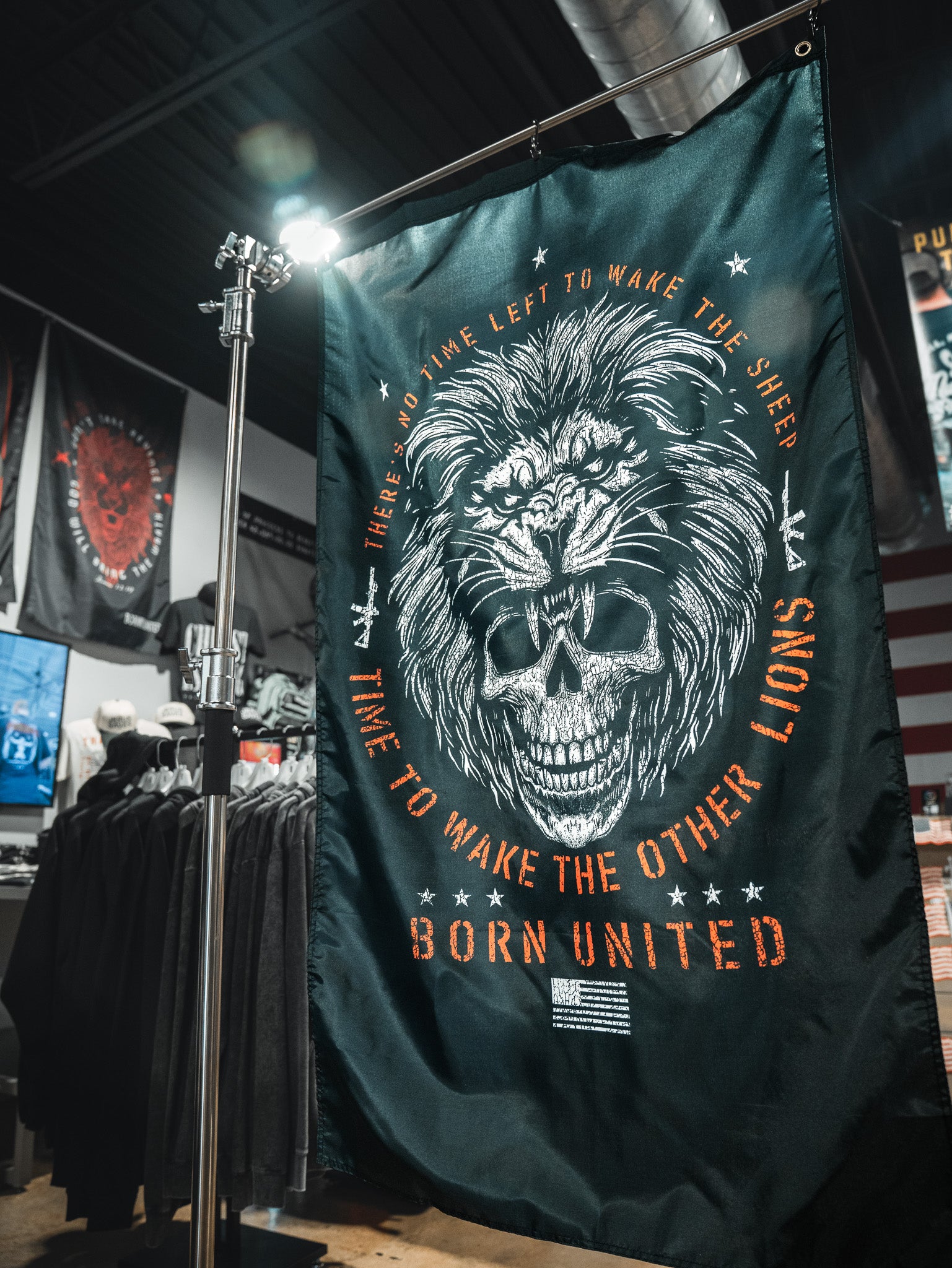 The Waking Lions Flag by Born United Private Label, crafted from durable polyester, shows a roaring lion merged with a skull and reads: "There's no time left to wake the sheep. Time to wake the other lions. Born United." Ideal for indoor display.