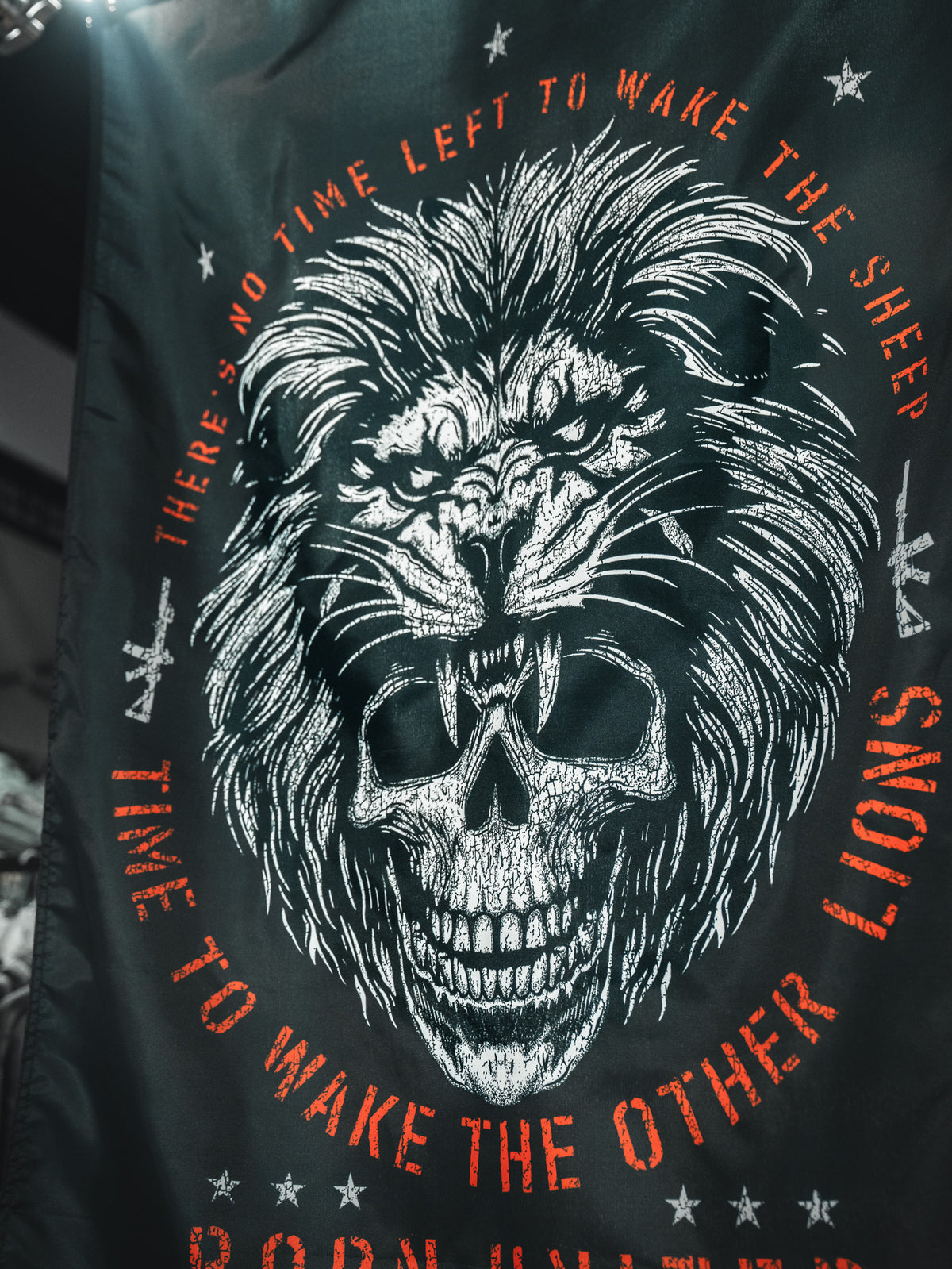 The Born United Private Label Waking Lions Flag features a black design with a white lion-skull face and bold red text: “THERE'S NO TIME LEFT TO WAKE THE SHEEP. IT'S TIME TO WAKE THE OTHER LIONS.” Made of durable polyester.