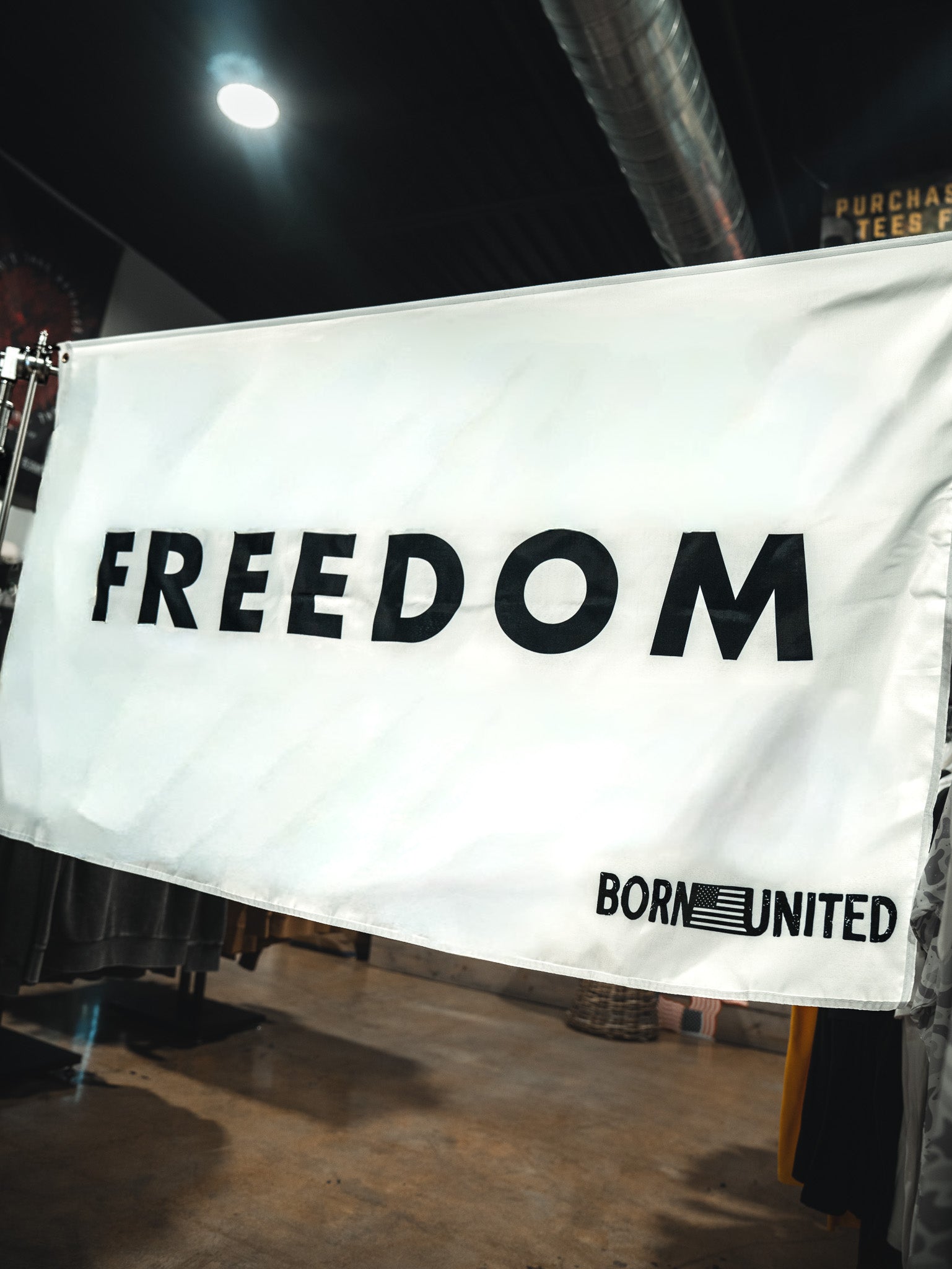 The Freedom Flag by Born United Private Label features bold black "FREEDOM," "BORN UNITED," and an American flag graphic on a white background, honoring patriotic values and American heritage in the bottom right corner.