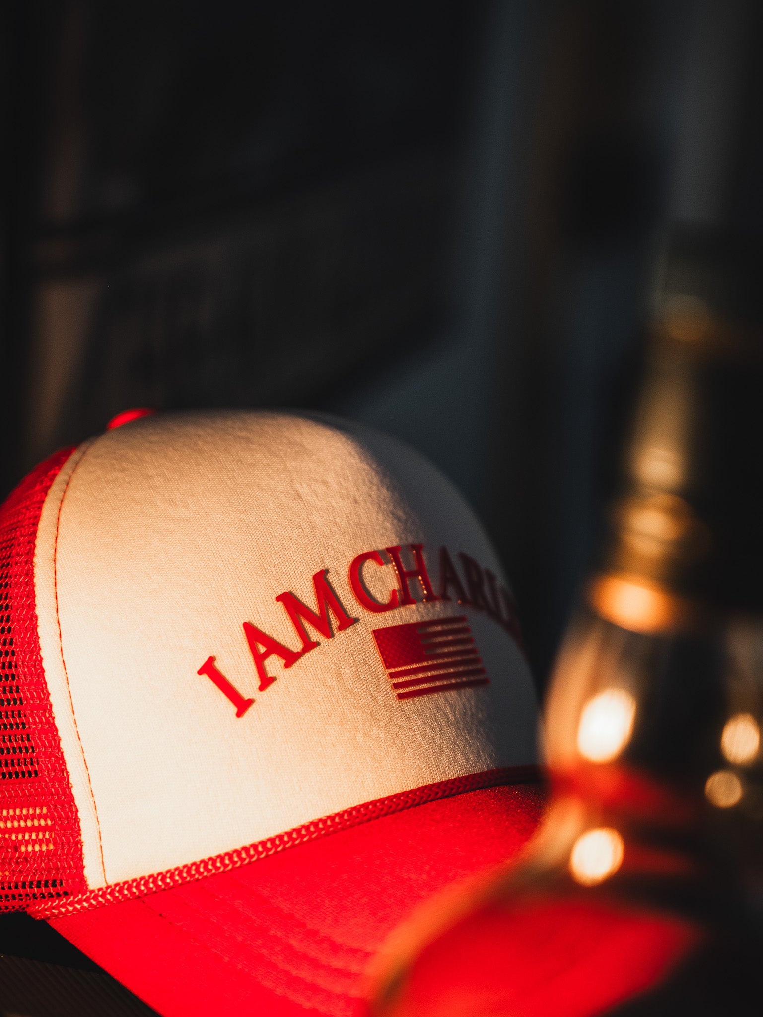 The Born United Private Label “I Am Charlie Red Trucker Snapback” features red and white panels, a curved brim, “I AM CHARL” text, and a stylized American flag on the front—adding bold style to any handmade hat collection.