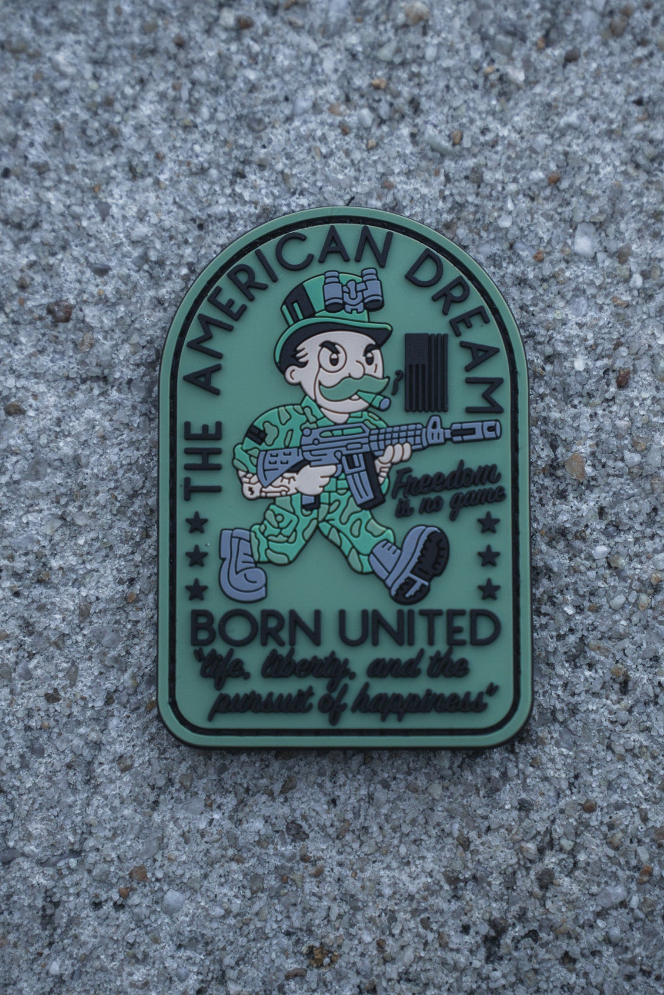 A cartoon soldier with a rifle decorates the American Dream PVC Patch by Born United Private Label, featuring "THE AMERICAN DREAM," "Born United," and "freedom to grab life, liberty, and the pursuit of happiness.
