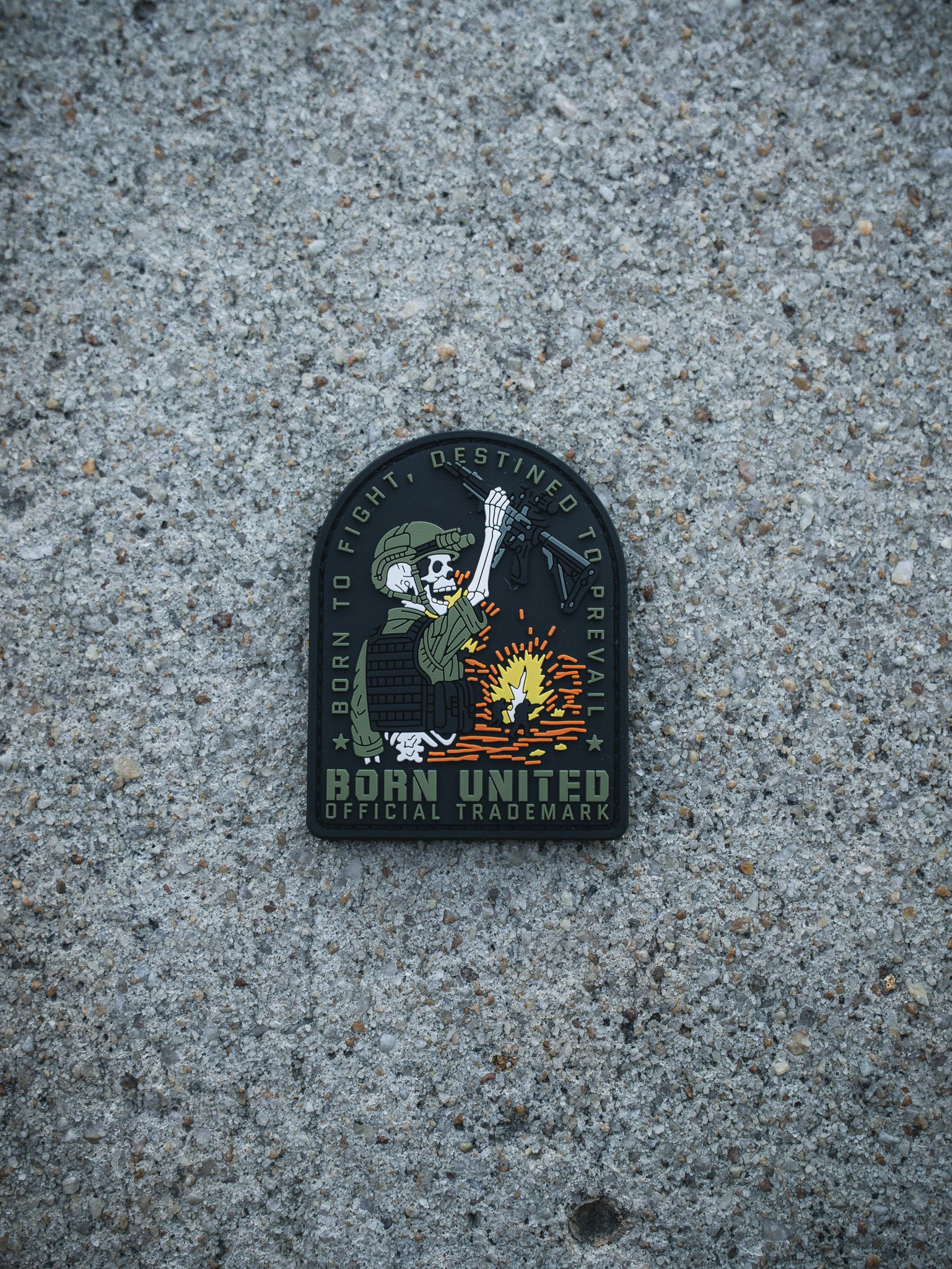The Destined to Prevail PVC Patch by Born United Private Label shows a skeleton in military gear raising a rifle over fire, with "BORN TO FIGHT, DESTINED TO PREVAIL" above and "BORN UNITED OFFICIAL TRADEMARK" below.