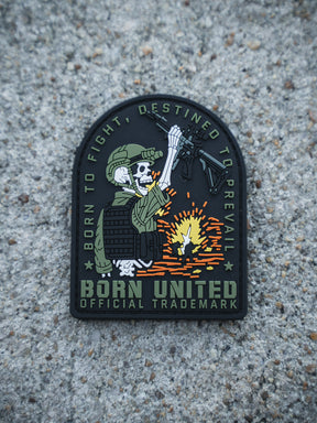 The Destined to Prevail PVC Patch by Born United Private Label shows a skeleton soldier in tactical gear firing a rifle with sparks. The patch features the slogans: BORN TO FIGHT, DESTINED TO PREVAIL, and BORN UNITED OFFICIAL TRADEMARK.
