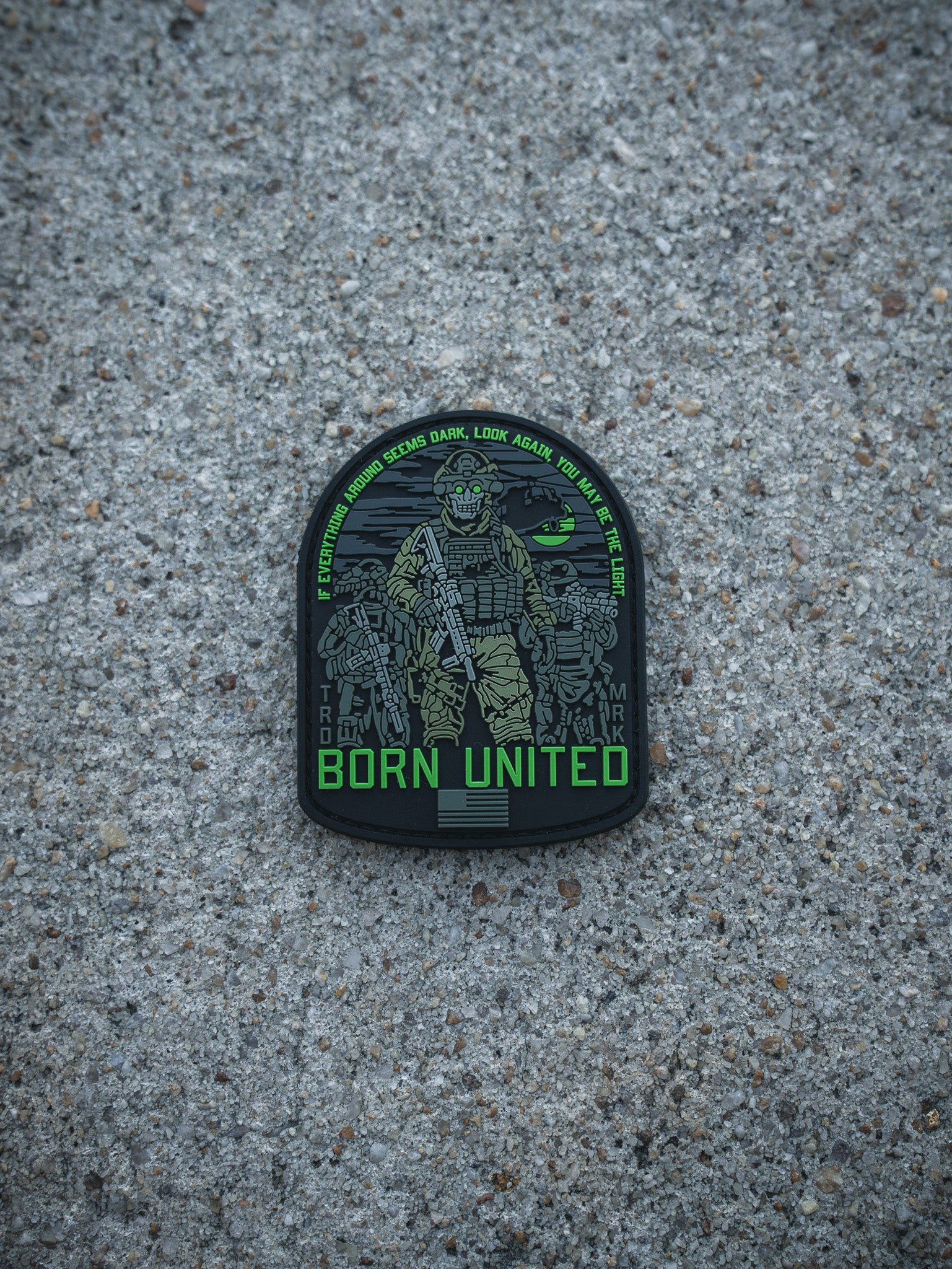 A patch by Born United Private Label, named "Light in the Darkness PVC Patch," features a heavily armed soldier with green accents on rough concrete. The text reads: IF YOU THINK LIGHT SEEMS DARK, LOOK AGAIN. YOU ARE THE LUCK. BORN UNITED below.