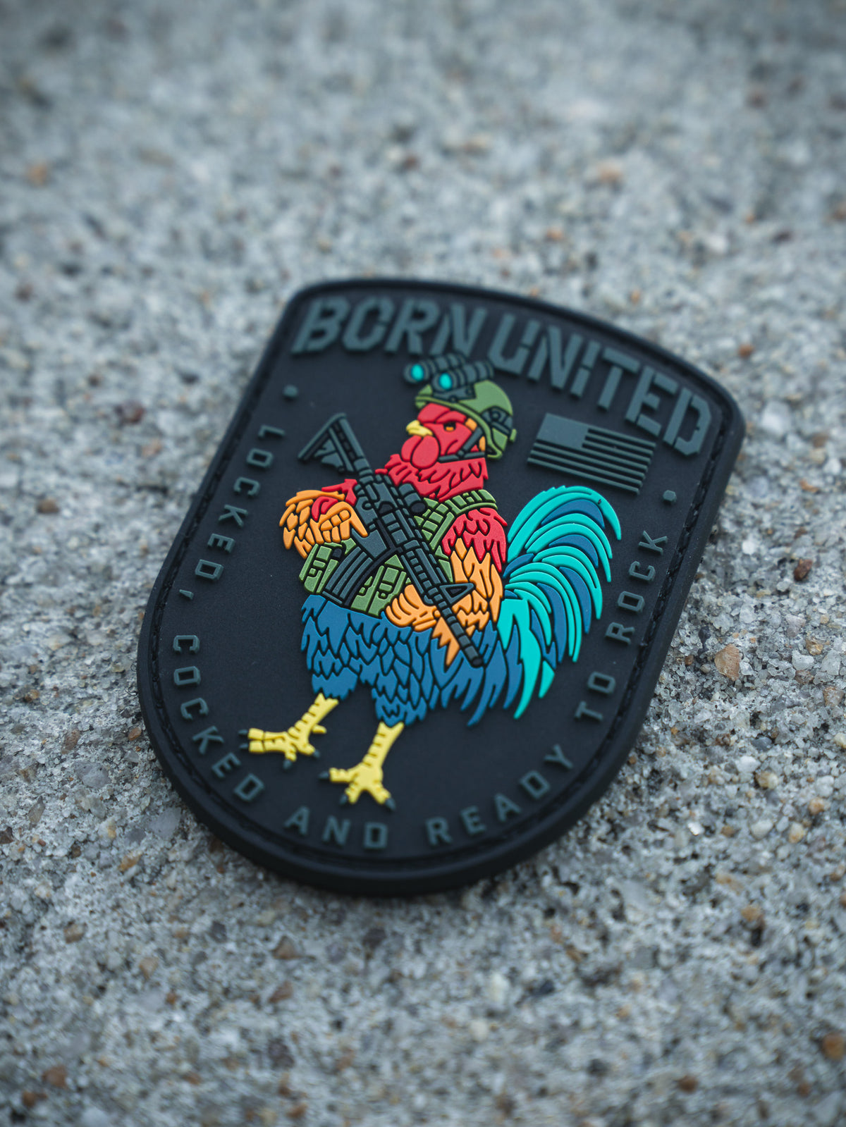 The Battle Bird PVC Patch by Born United Private Label features a rooster in military gear with a rifle, displaying "BORN UNITED" at the top and "LOCKED, COCKED AND READY TO ROCK" around the bottom edge.