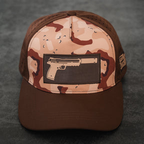 The Choco Chip Silencer Hydro Snapback Hat by Tango Charlie Apparel features brown and tan colors with a rectangular patch showing a handgun outline, displayed on a dark textured surface.