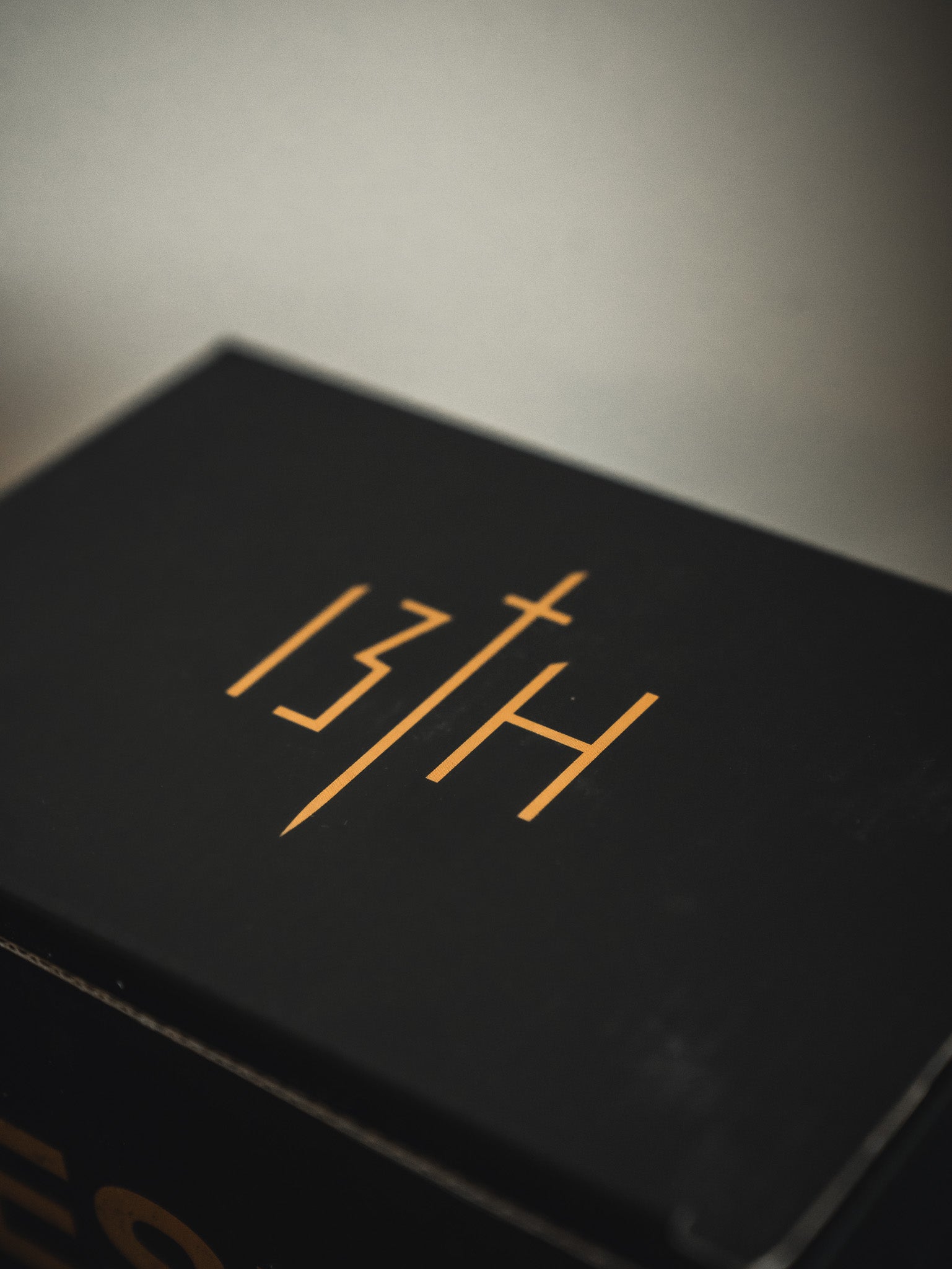A black 13th box, featuring gold "13TH" with a cross-shaped "T," sits next to a Jesus Saves Mug by 13th. Both are set against a blurred neutral background.