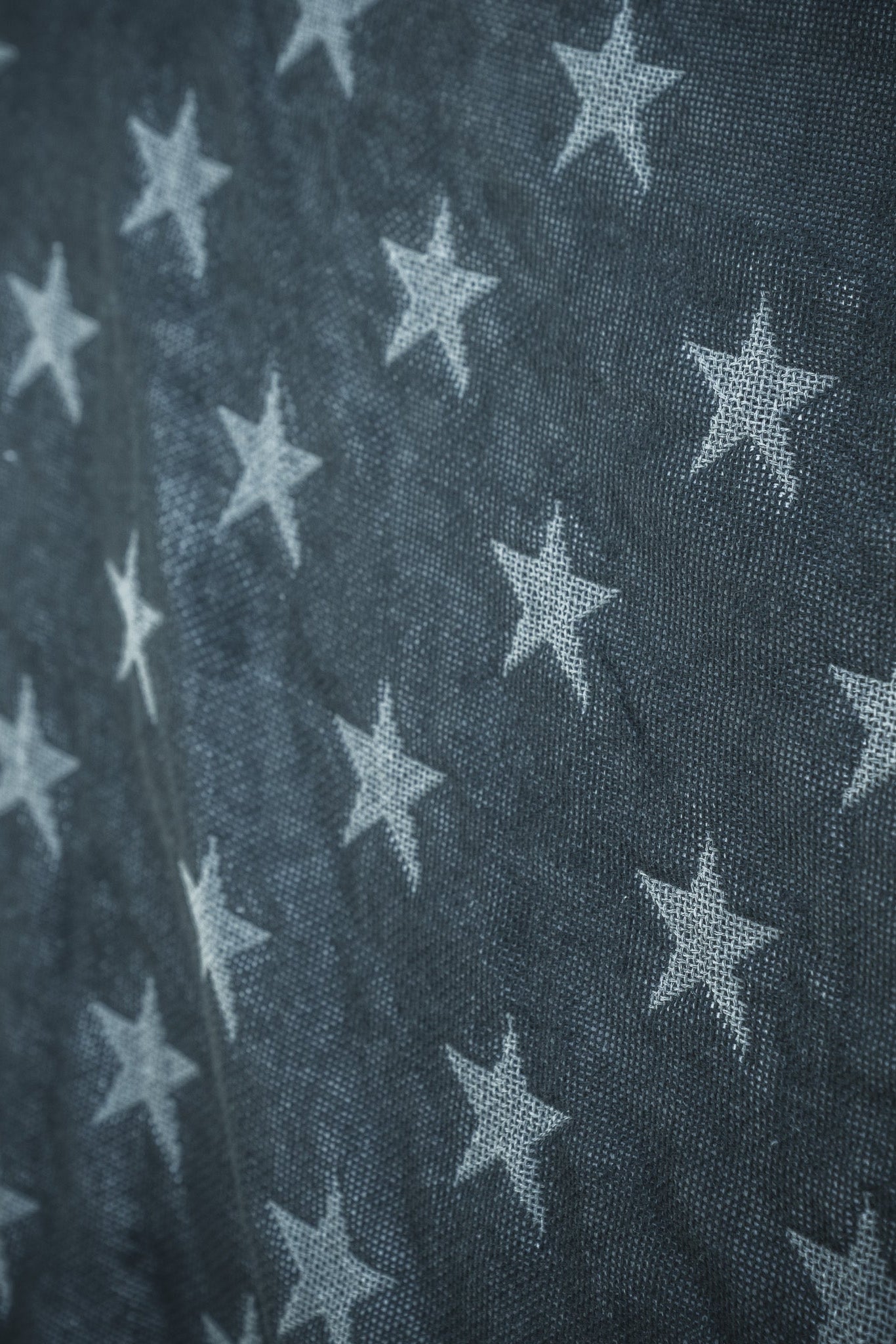 Close-up of the Born United Private Label Blackout American Flag Jacquard Blanket, showing its textured blue fabric with neatly arranged white stars in rows, resembling part of the American flag.