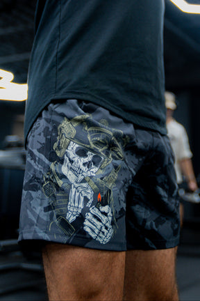 A person wears Born United Private Labels Mens Performance Hybrid Shorts 5.5 | Savage Ops, featuring a skeleton in tactical gear holding a lighter with a red flame; the blurred background highlights the unique design.