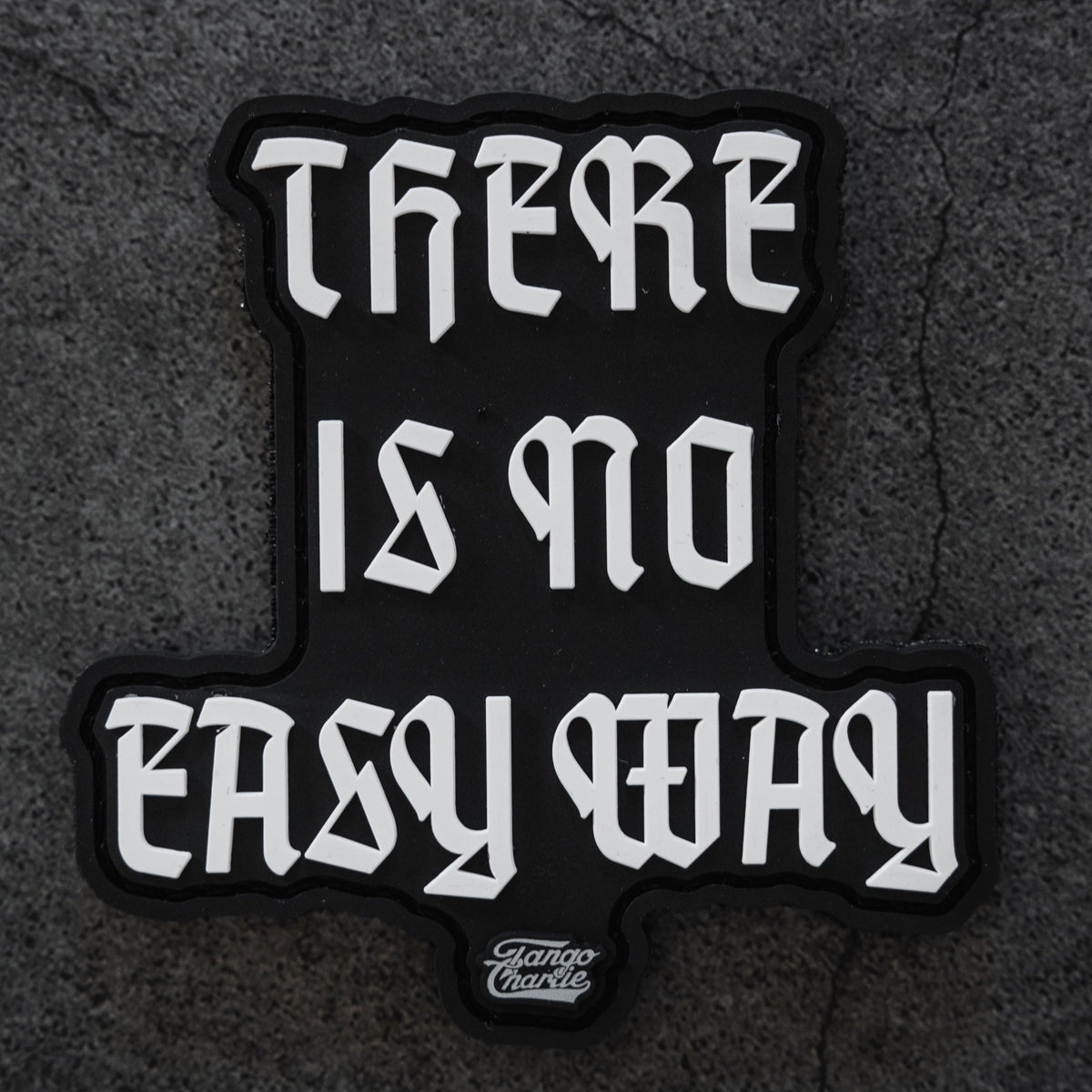 The "There’s no easy way" patch by Tango Charlie Apparel is a 3-inch black 3D PVC Velcro patch with bold white gothic lettering and features Tattoo Charlie in small text at the bottom.