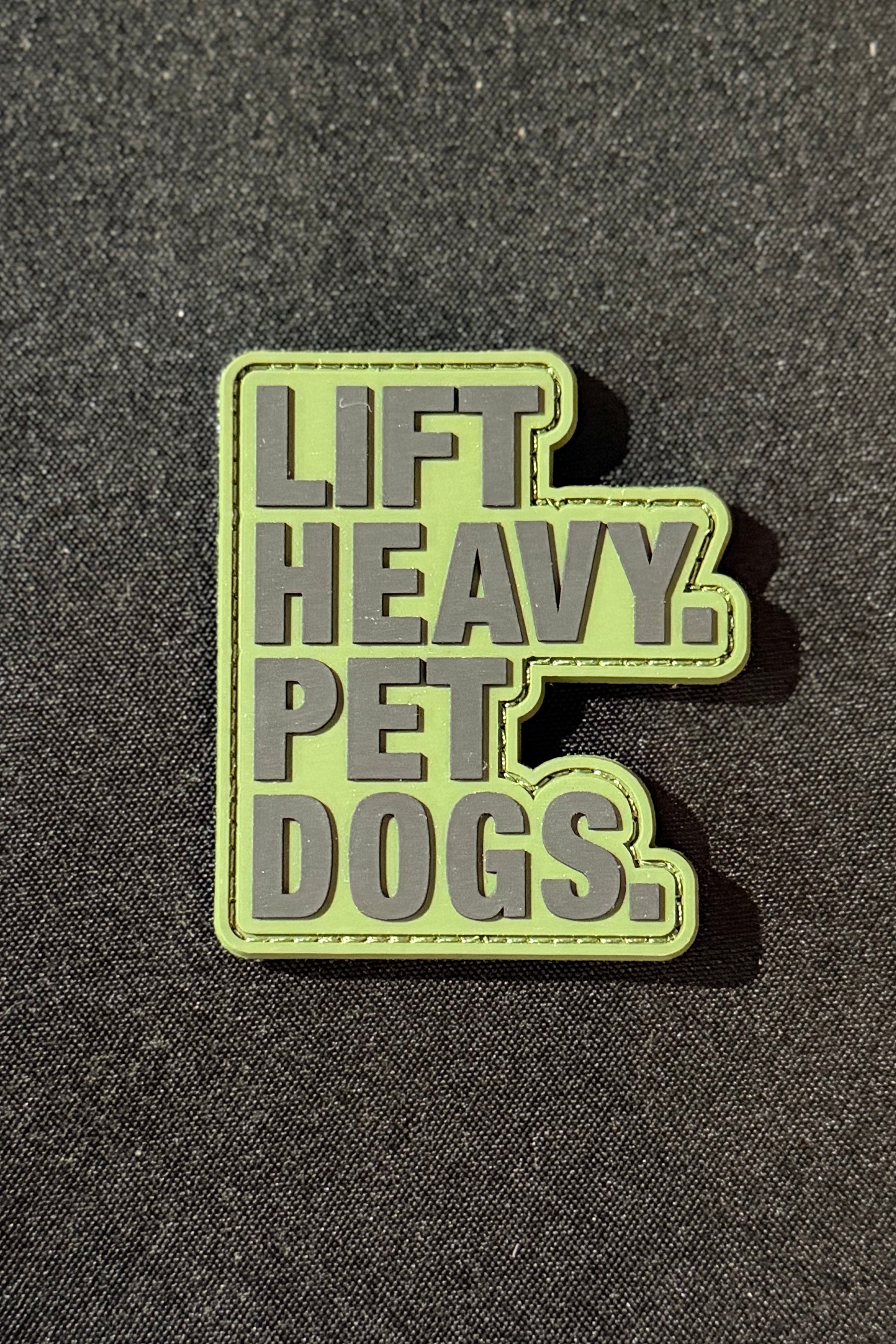 Rectangular Lift Heavy. Pet Dogs Patch in PVC with a light green background and dark grey raised text reading LIFT HEAVY. PET DOGS.