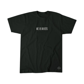 The He is Risen Premium Tee by 13th features bold, gothic "HE IS RISEN" text centered on a black shirt, with a small white 13th logo near the hem—a sleek, inspiring Christian resurrection tee.