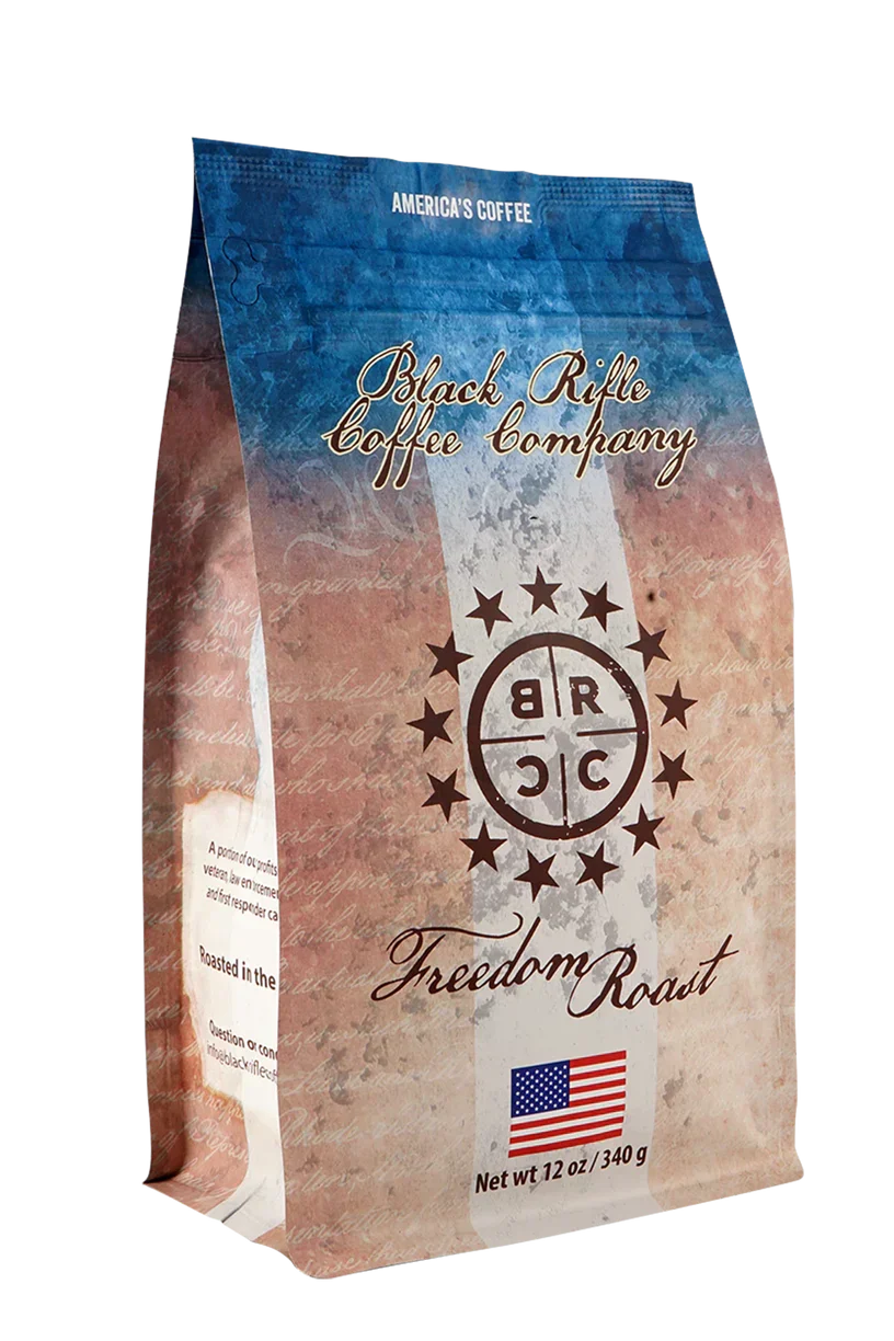 Black Rifle Coffee’s Freedom Roast Ground 12 oz features a rustic American flag design, brand logo, and a hint of milk chocolate flavor in every cup. A small American flag is displayed at the bottom of the packaging.