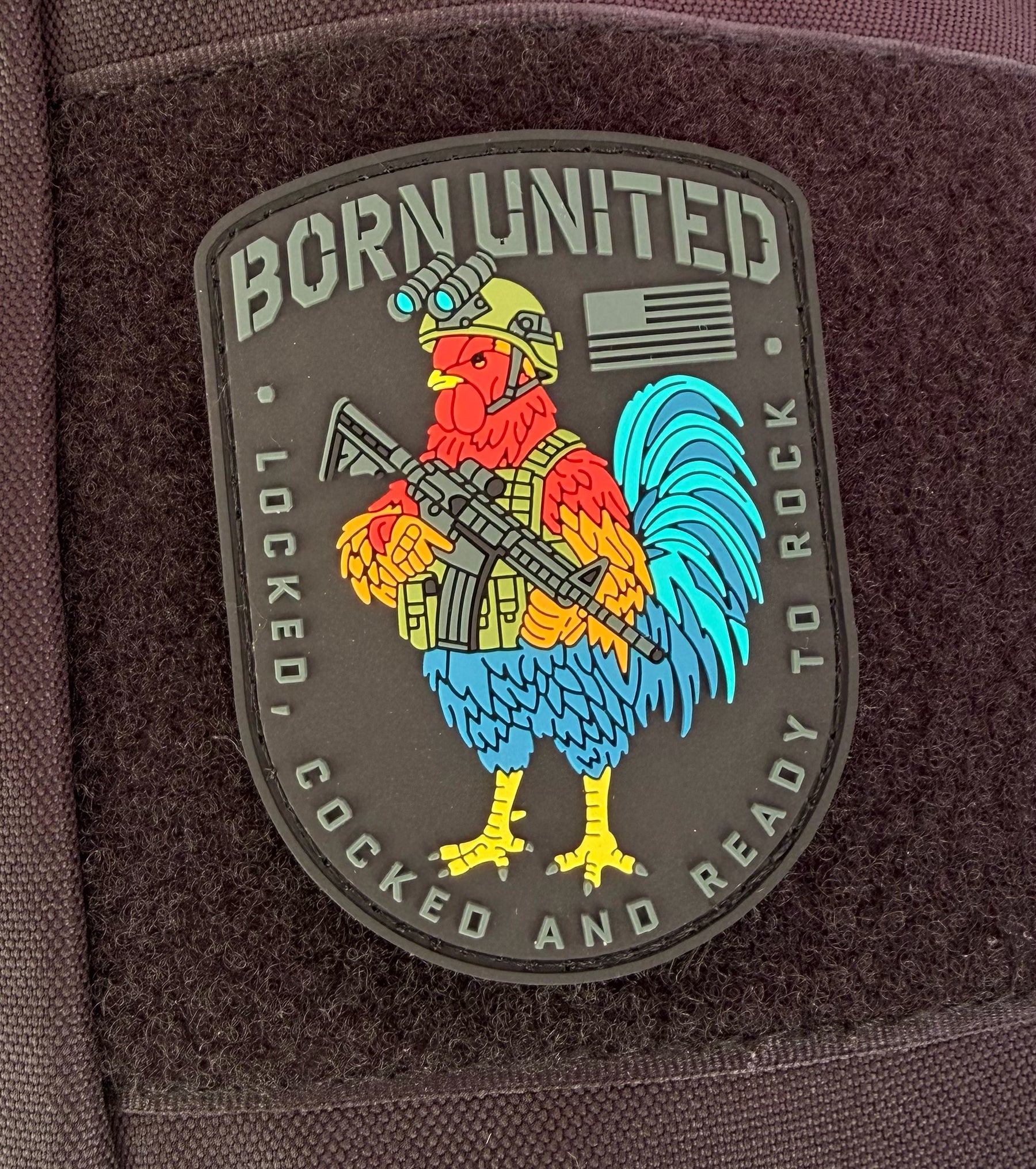 The Battle Bird PVC Patch by Born United Private Label features a rooster in military gear with a rifle, an American flag, and the text "BORN UNITED" on top and "LOCKED, COCKED AND READY TO ROCK" at the bottom.