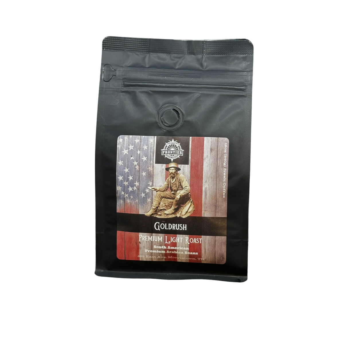 A black coffee bag labeled Frontier Coffee Gold Rush Light Roast - Whole Bean features a gold miner and American flag illustration, evoking the American Dream. This single origin Guatemalan coffee is sealed and stands upright on a white surface.